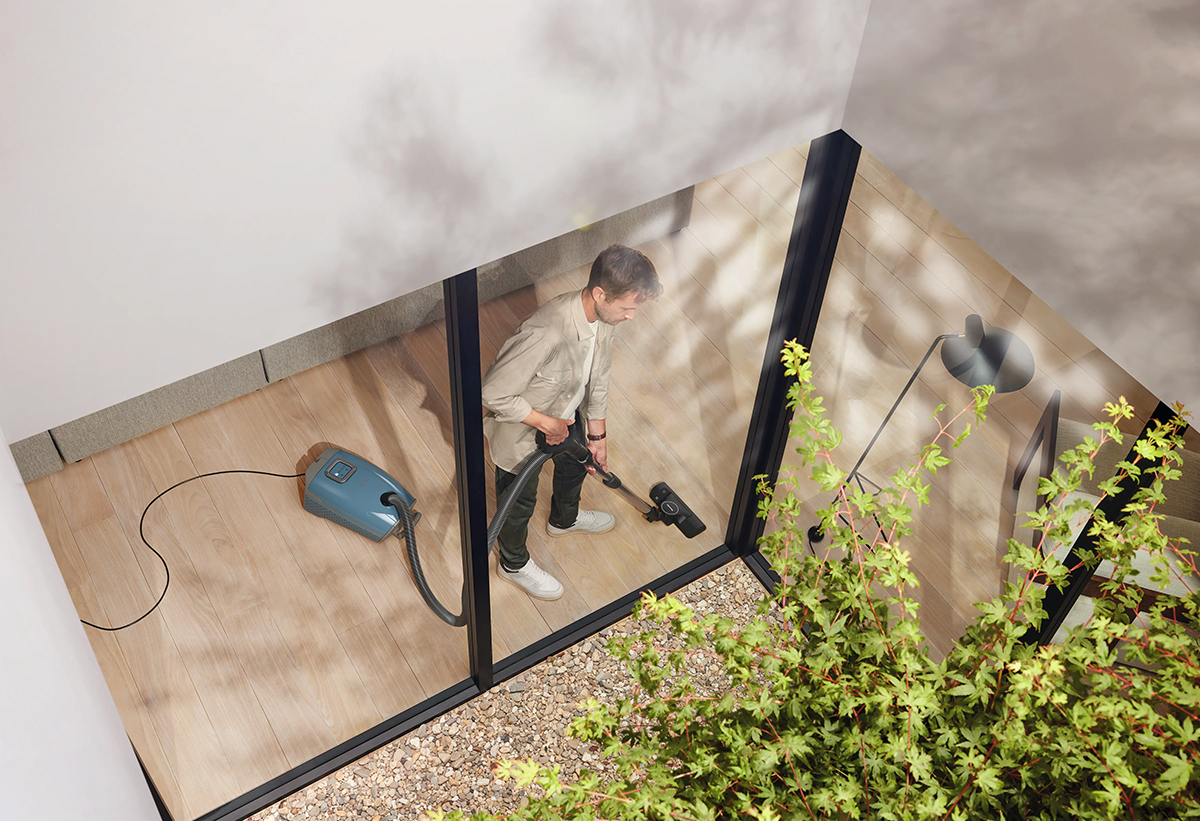 Ένας άντρας καθαρίζει το πάτωμα του σπιτιού του με τη σκούπα.